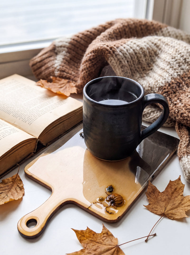 Salem Board beneath a black mug beside an open book and autumn leaves