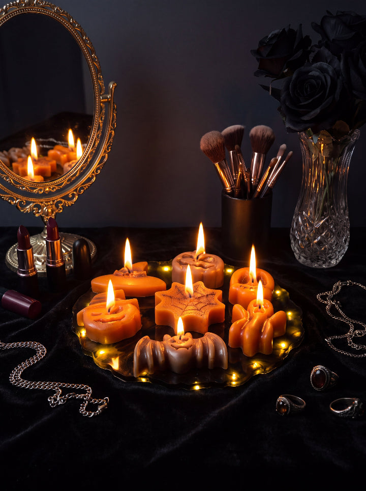 Spellbound Halloween beeswax candle set on an illuminated resin stand beside a gold mirror, black roses and jewellery.
